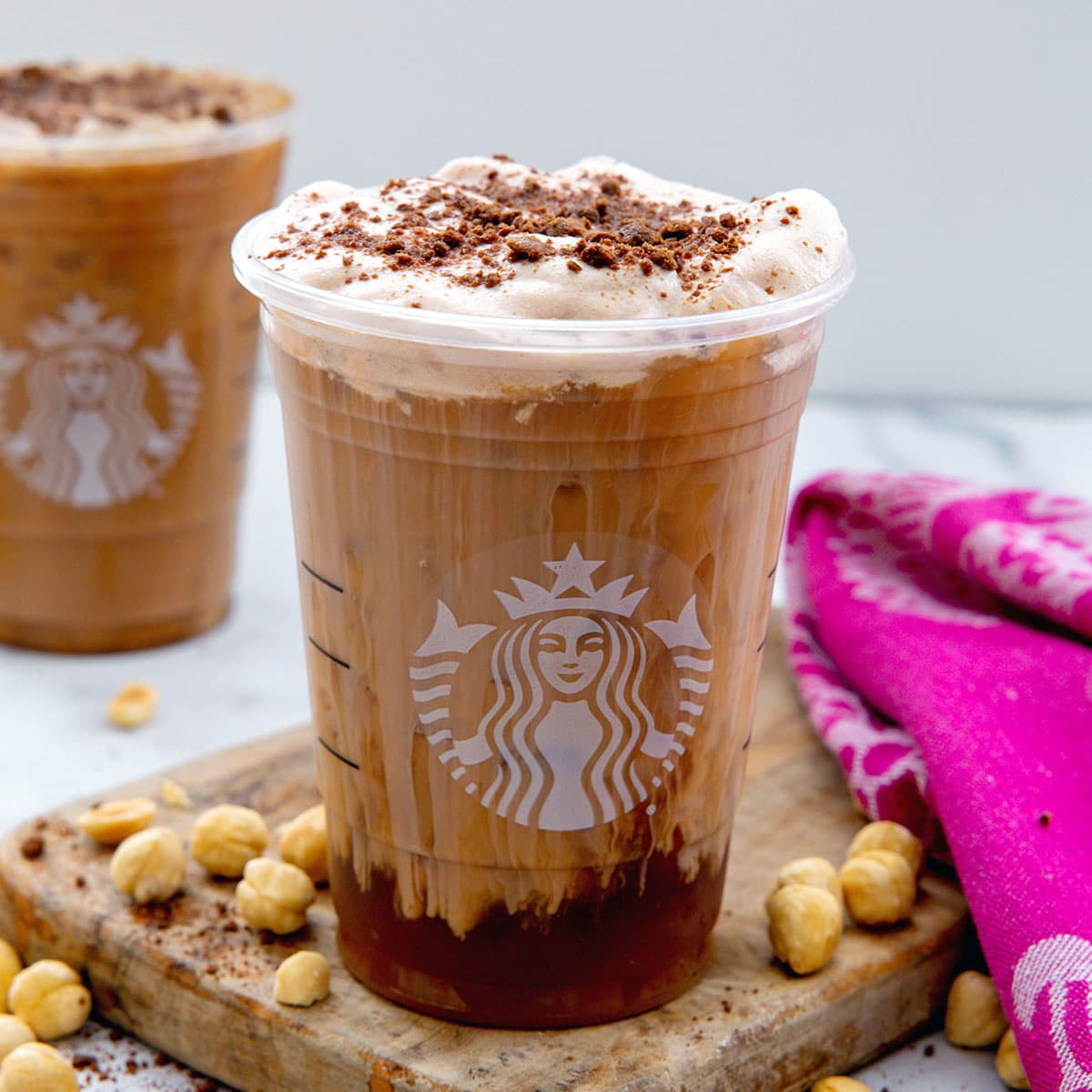 Closeup view of a Starbucks Chocolate Hazelnut Cookie Cold Brew with hazelnuts all around.