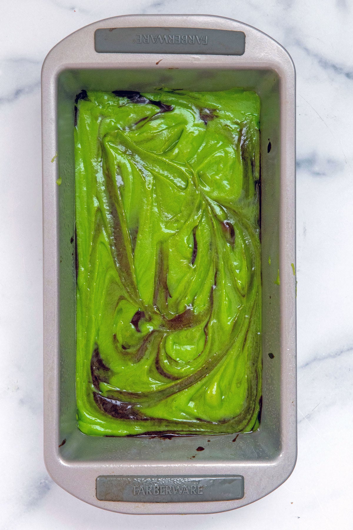 Green pistachio batter and chocolate batter swirled together in loaf pan.