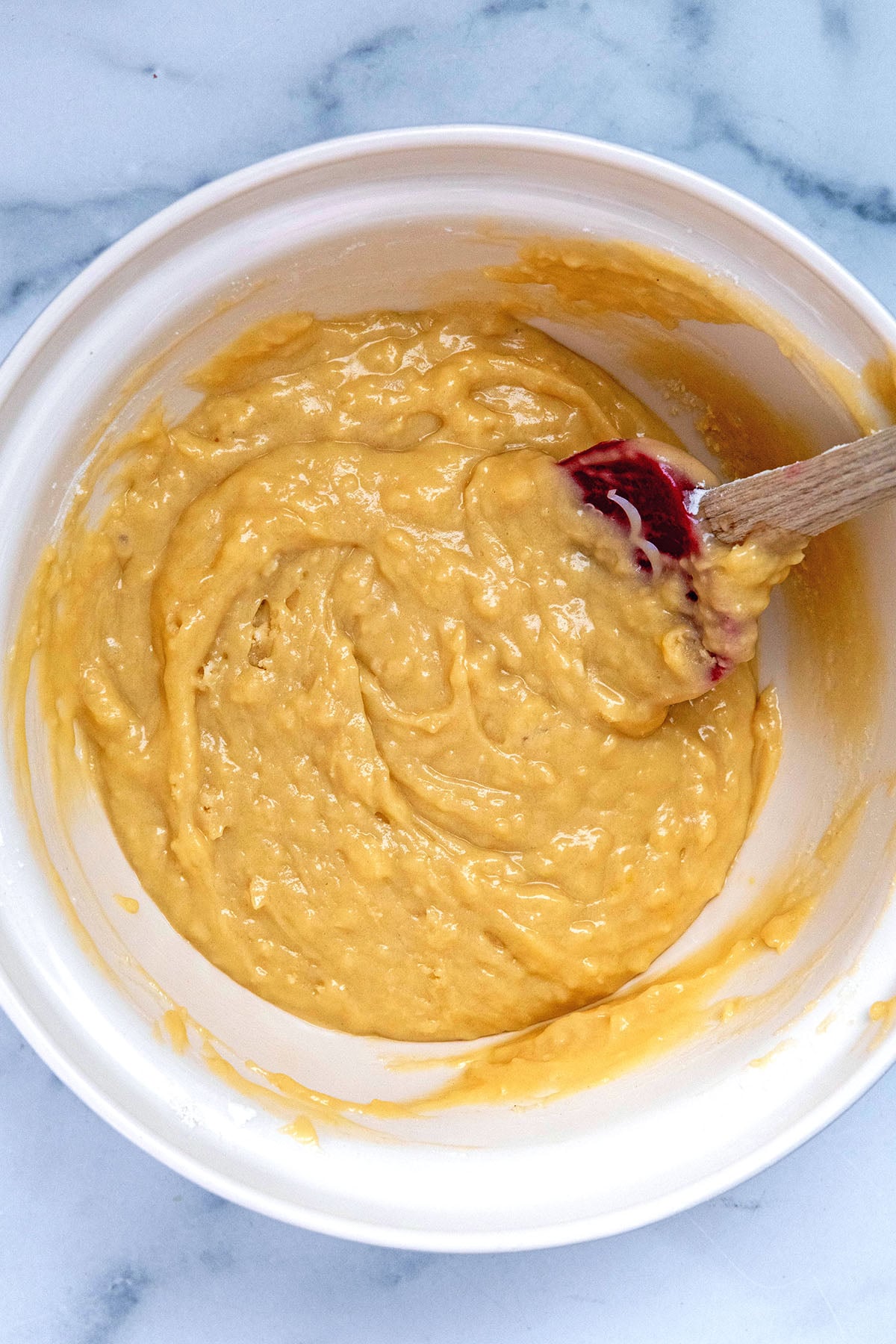 Loaf batter mixed together in bowl with wooden spoon.