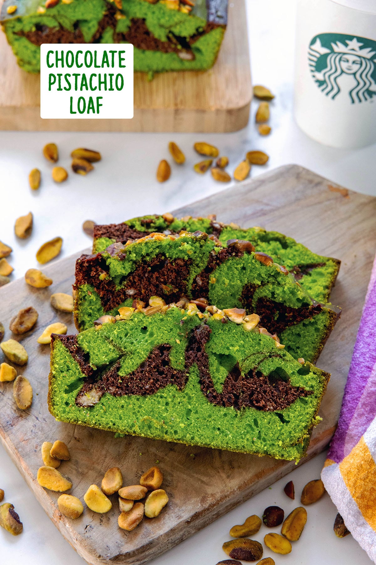 Overhead view of slices of chocolate pistachio loaf on a wooden board with loaf and Starbucks coffee cup in background and recipe title at top.