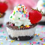 Head-on view of a chocolate strawberry ice cream cake cupcake with whipped cream, a fresh strawberry, and sprinkles.