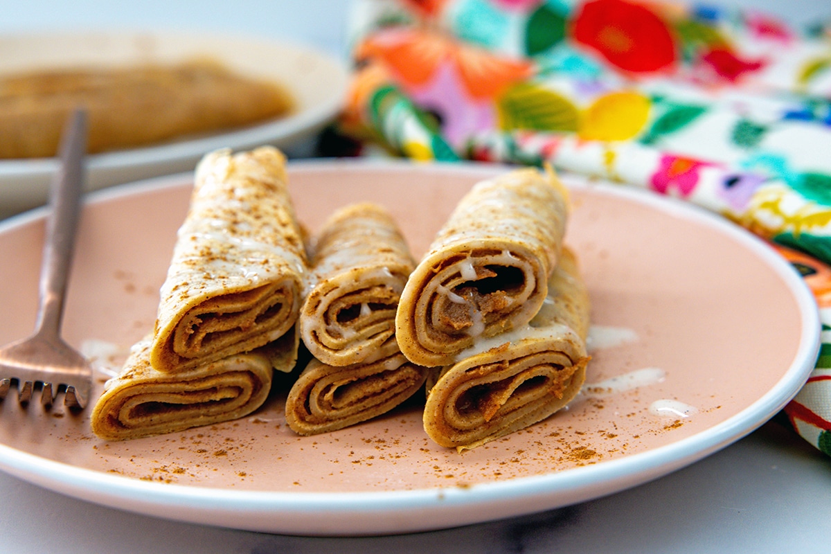 Head-on view of rolled up cinnamon roll crepes to show filling.