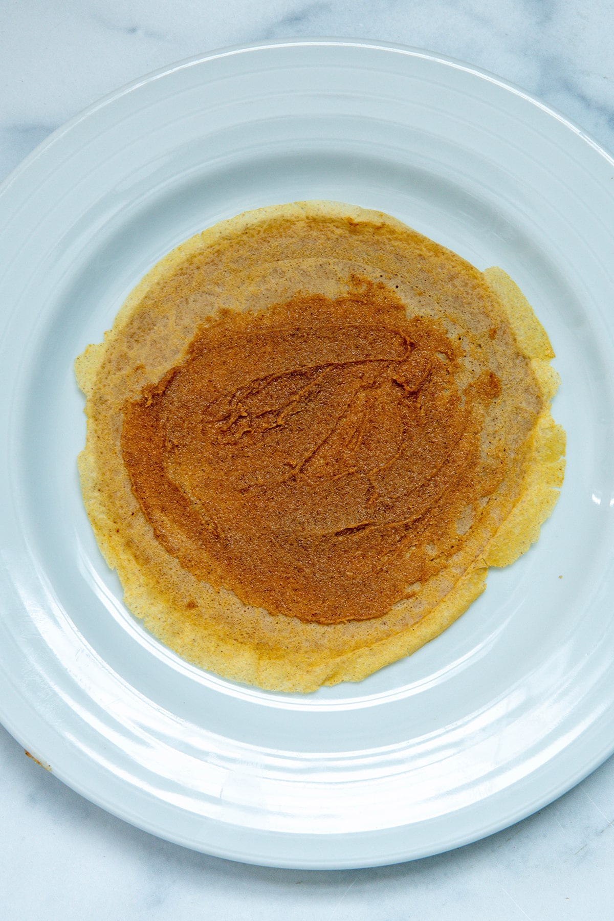 Buttery cinnamon sugar filling spread on a crepe.