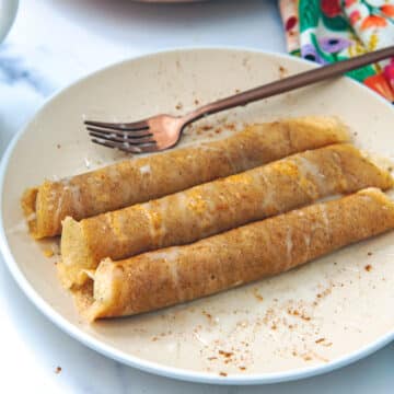 Closeup view of a plate of rolled up cinnamon roll crepes.