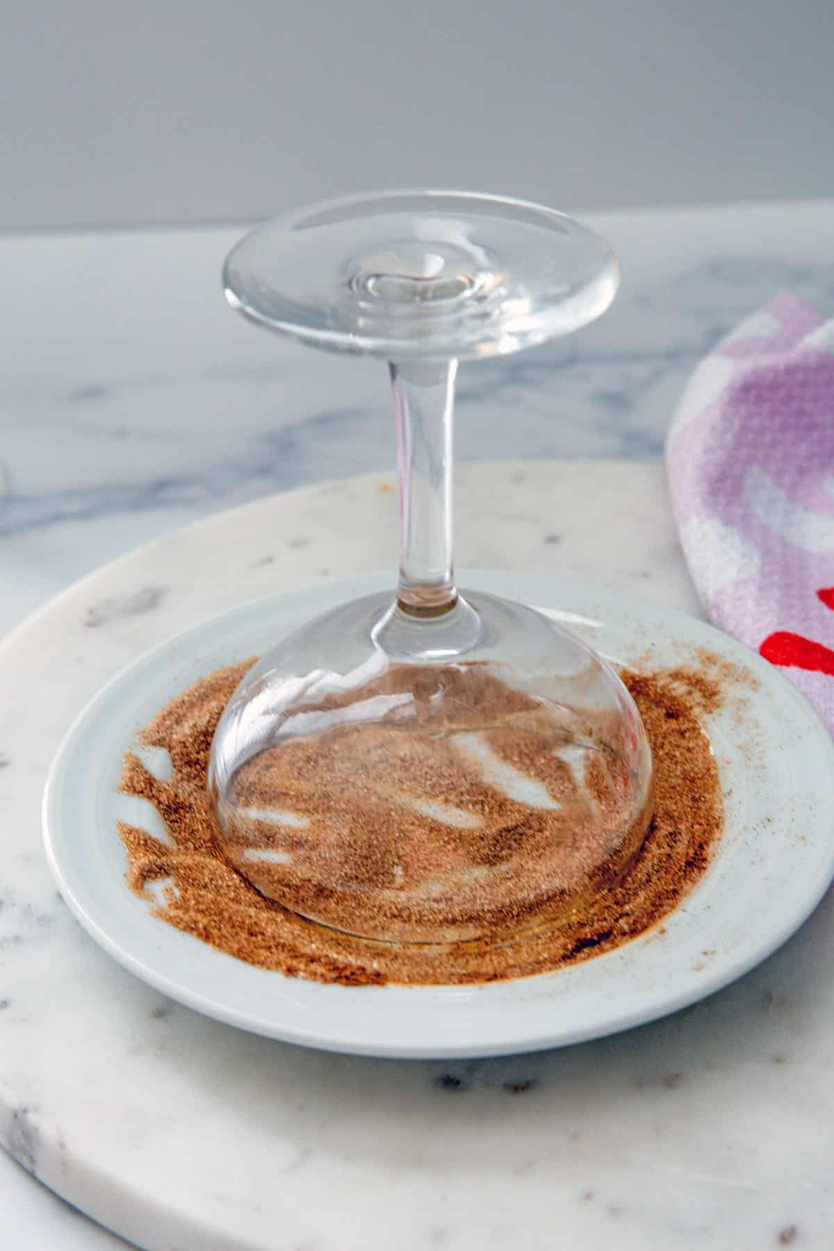 Coupe glass upside-down on a small plate of cinnamon sugar.