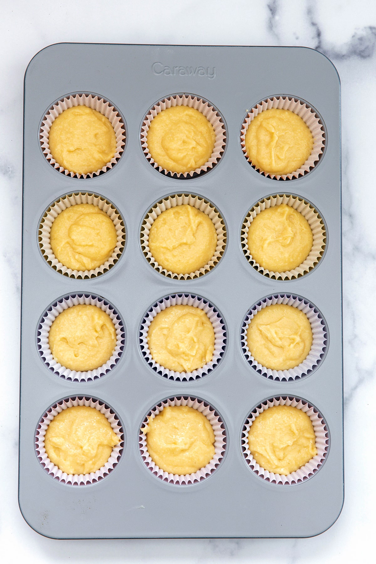 Cupcake batter spooned over cinnamon sugar mixture in cupcake tin.