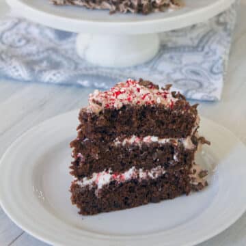 Closeup of a slice of chocolate cake made with cocoa pebbles and with a marshmallow frosting with crushed candy canes on it.