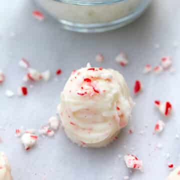 Closeup view of a coconut candy cane truffle with crushed candy canes all around.