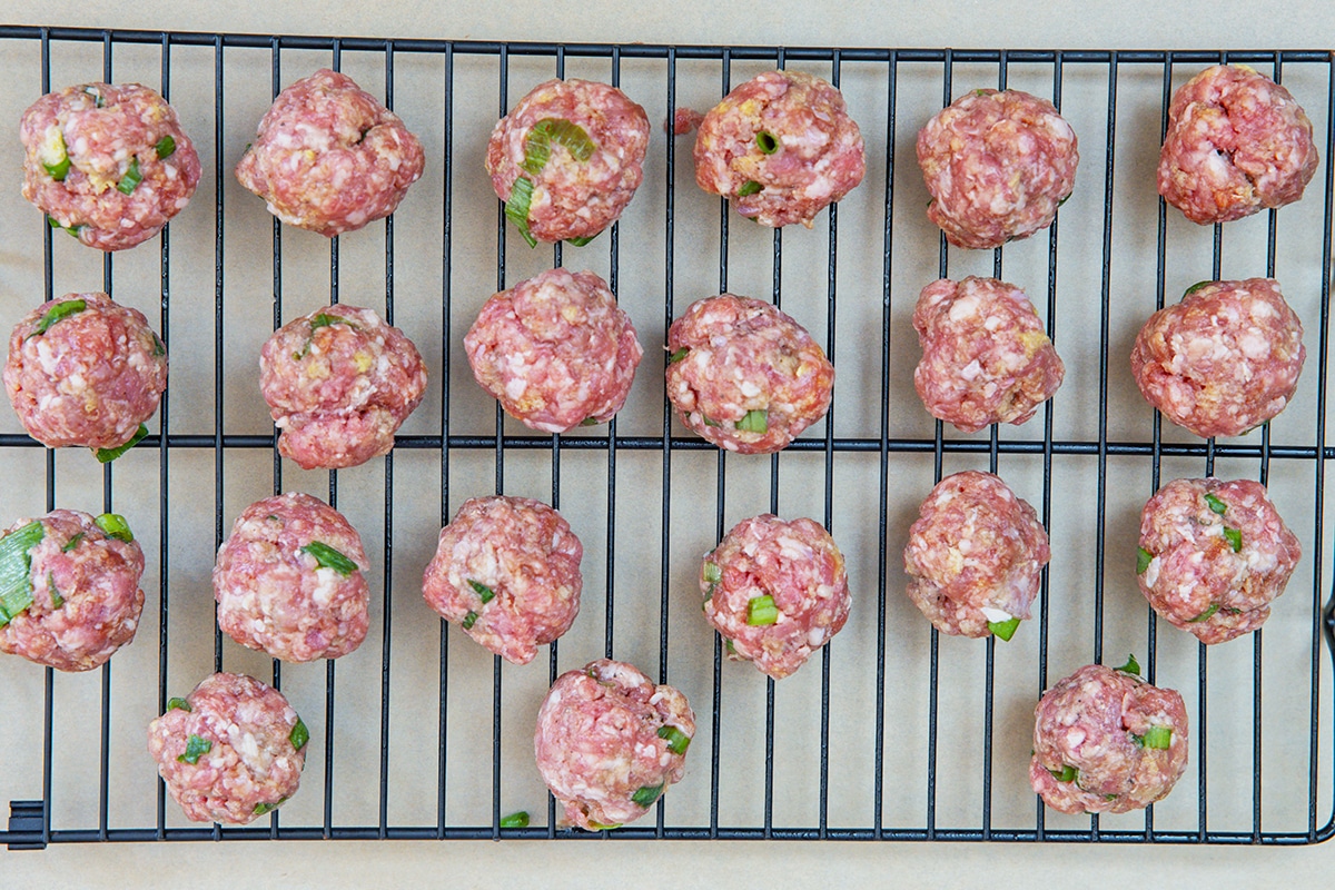 Meatballs formed and sitting on baking rack.