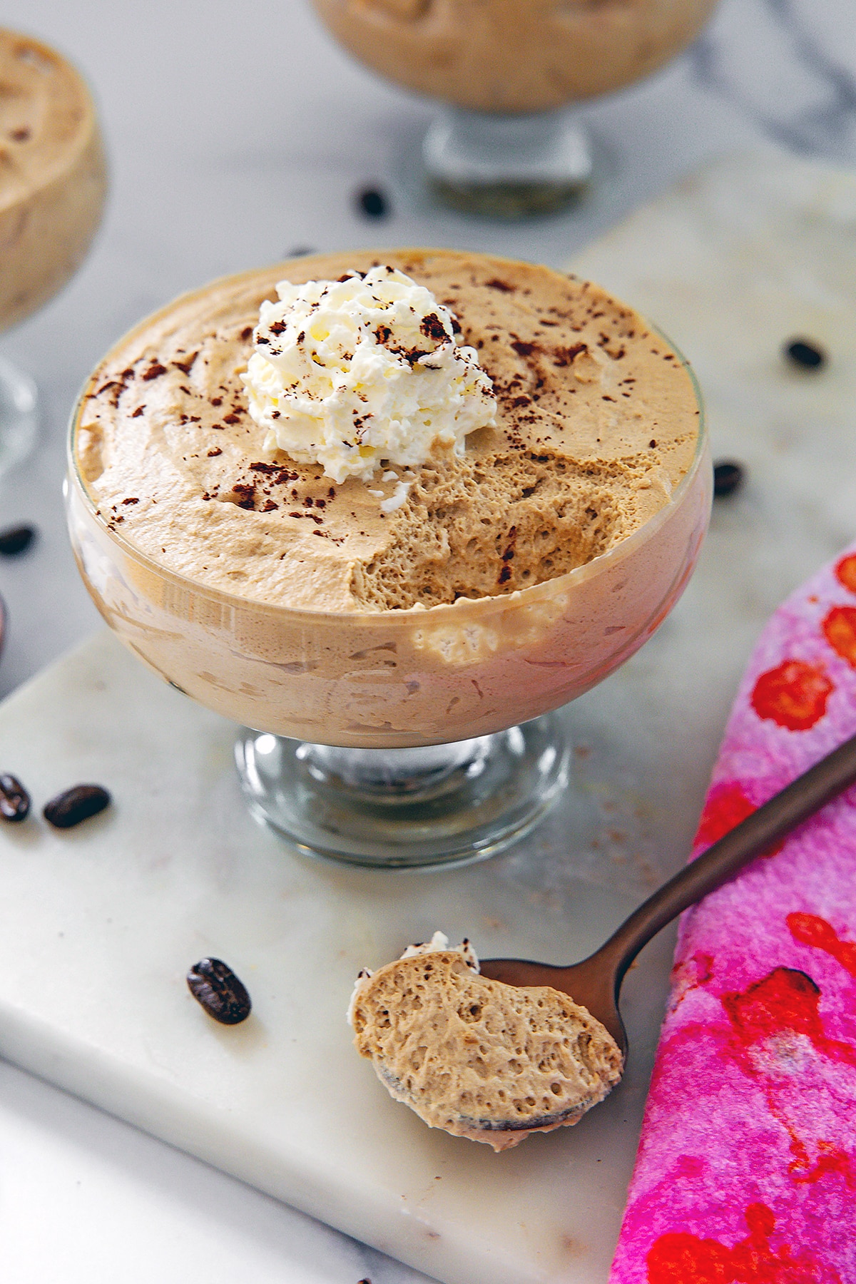 Glass ramekin of coffee mousse with spoonful of it on the side.
