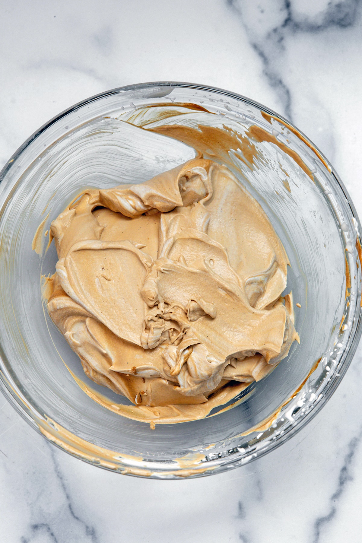 Espresso mixed into whipped cream in bowl.