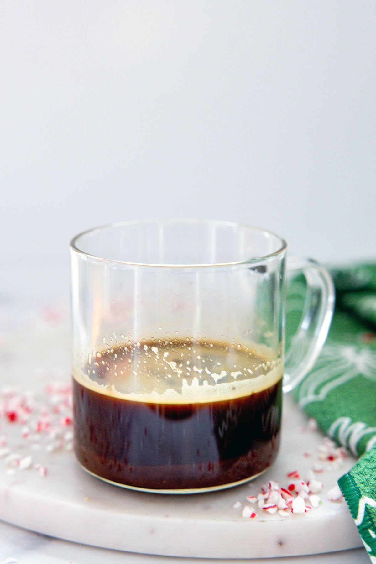 Head-on view of a clear mug with espresso and peppermint syrup.