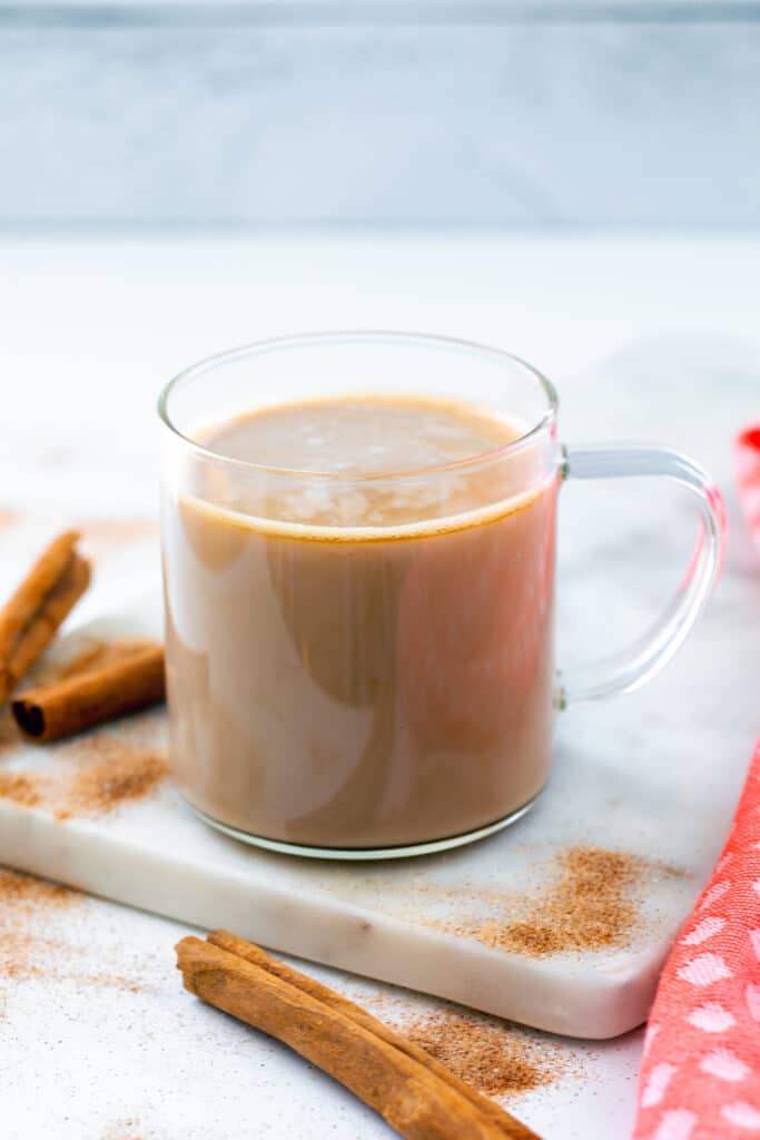 Clear mug with espresso, cinnamon syrup, and steamed milk.