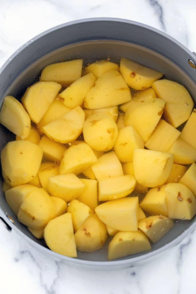 Chopped potatoes in pot with water.