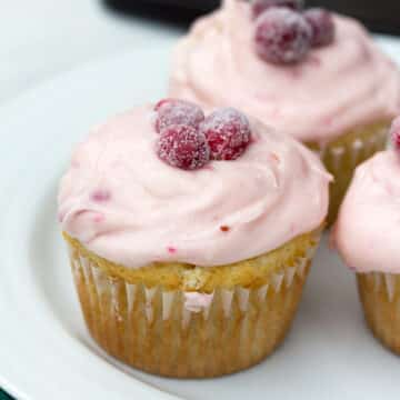 Closeup view of a cranberry champagne cupcake topped with sugared cranberries.
