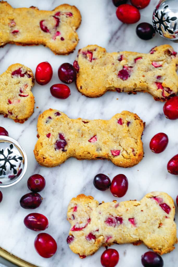 Cranberry dog treats on a marble platter with fresh cranberries all around.