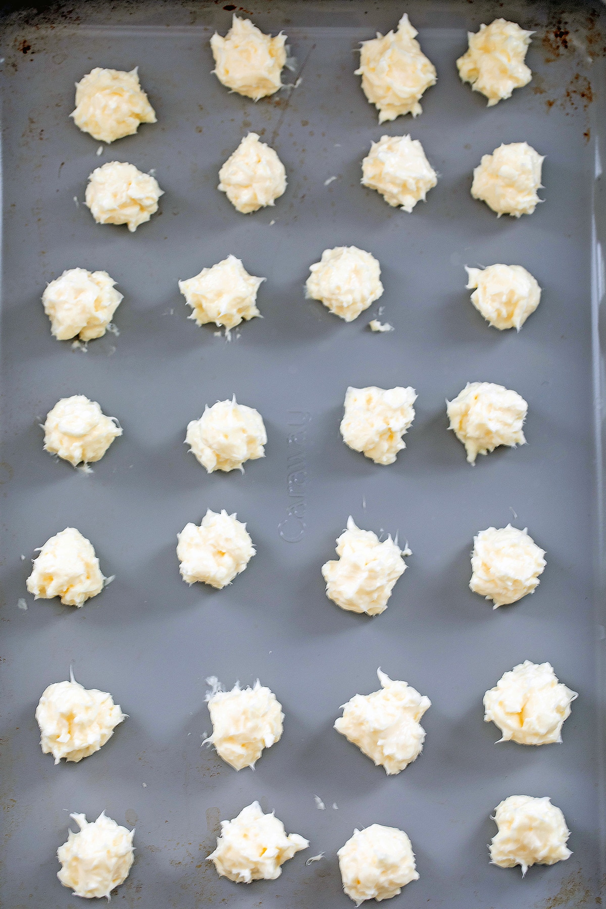Cream cheese balls lined up on baking sheet.