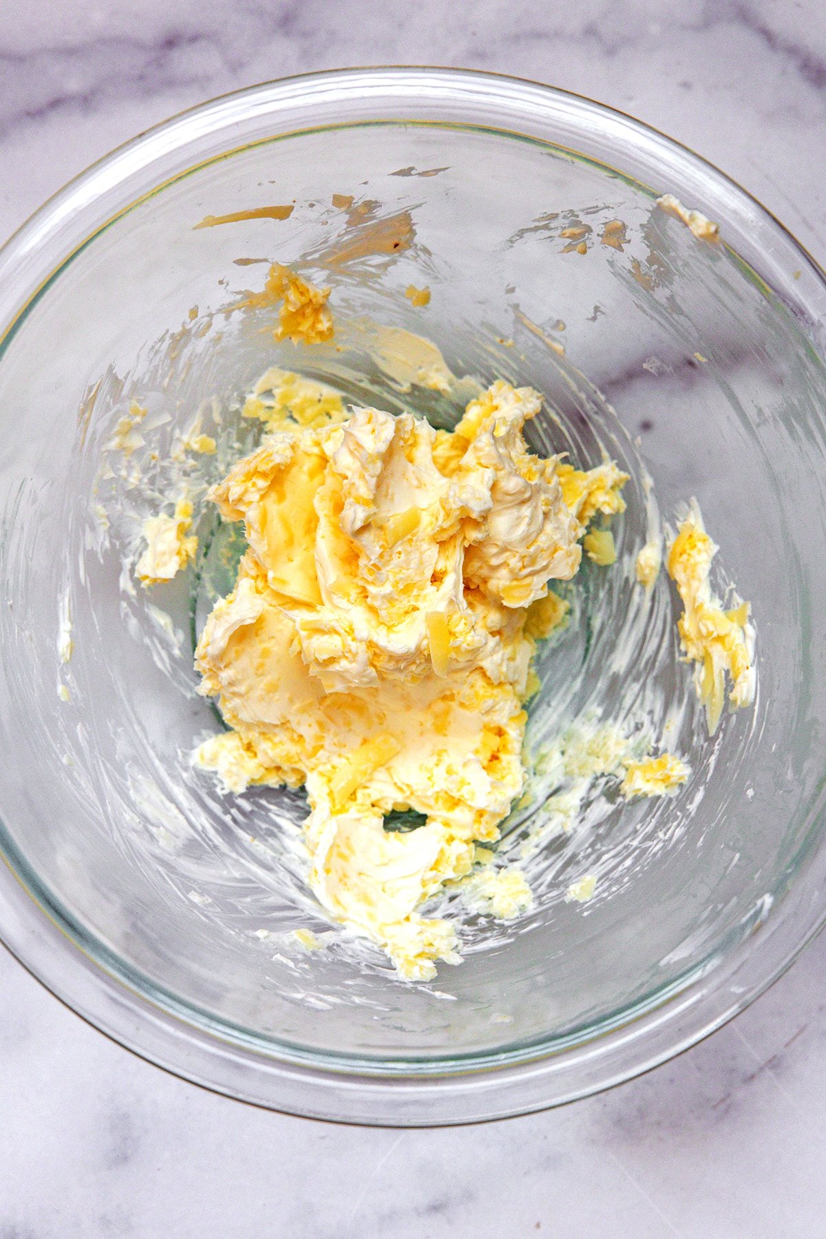 Cream cheese and shredded cheddar mixed together in bowl.