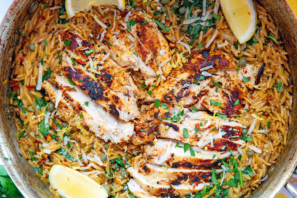 Overhead closeup view of creamy lemon chicken orzo in a skillet.