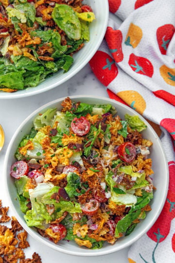 Bird's eye view of a bowl of crispy BLT pasta salad with second bowl in background and crispy pasta on the side.