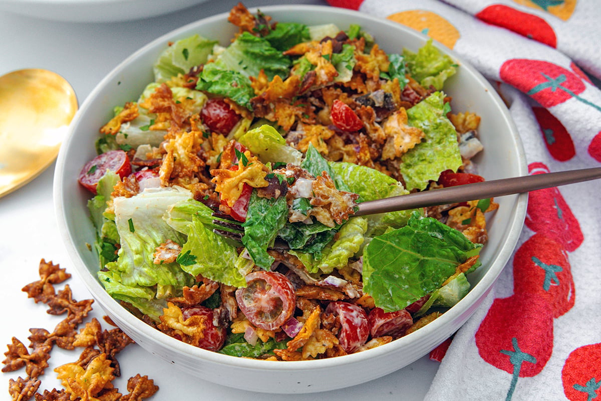 Landscape closeup view of a crispy BLT pasta salad with fork in it.