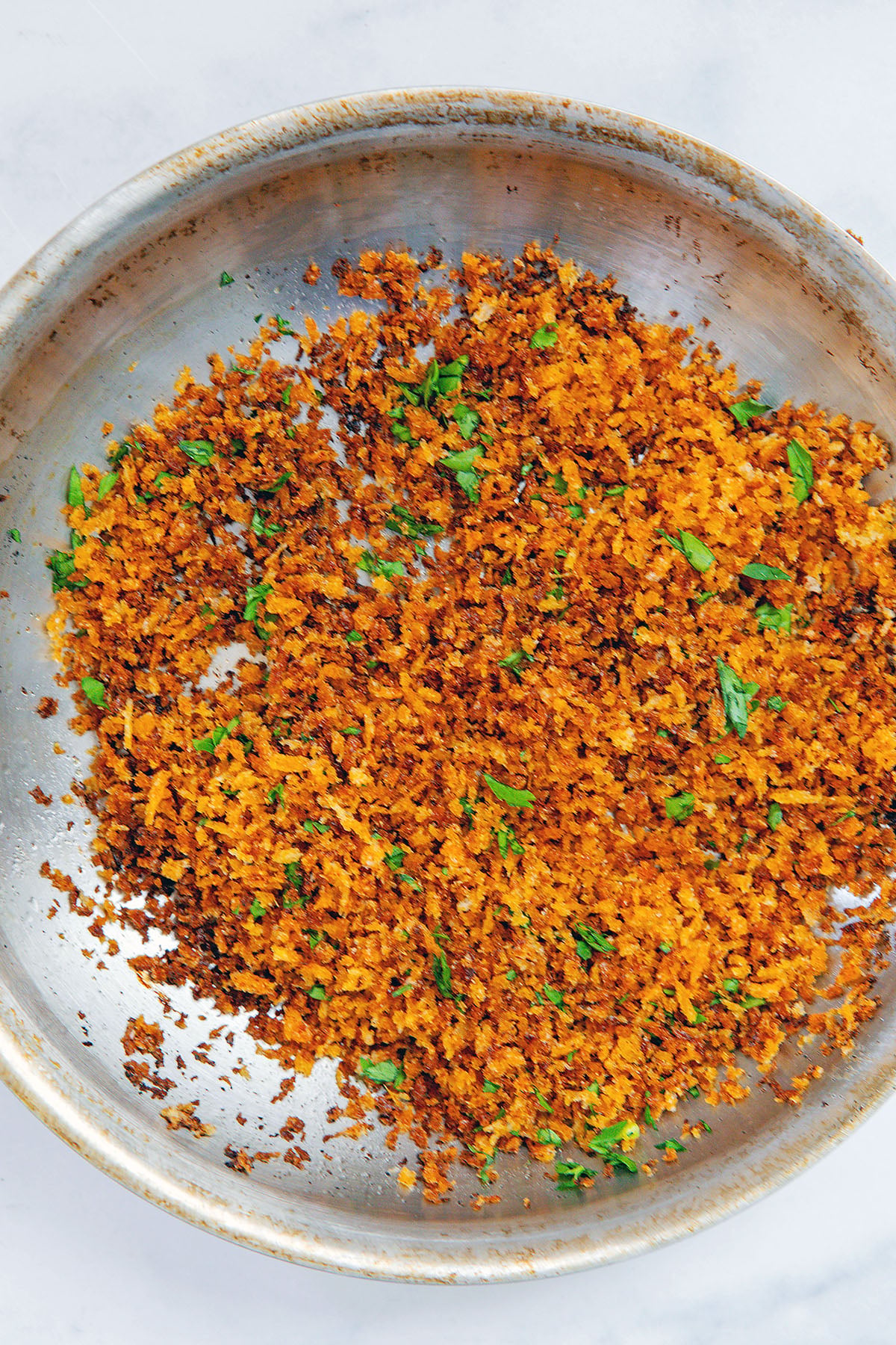 Crispy panko topping with parsley in skillet.