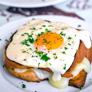 Closeup view of a croque madame with egg on top.