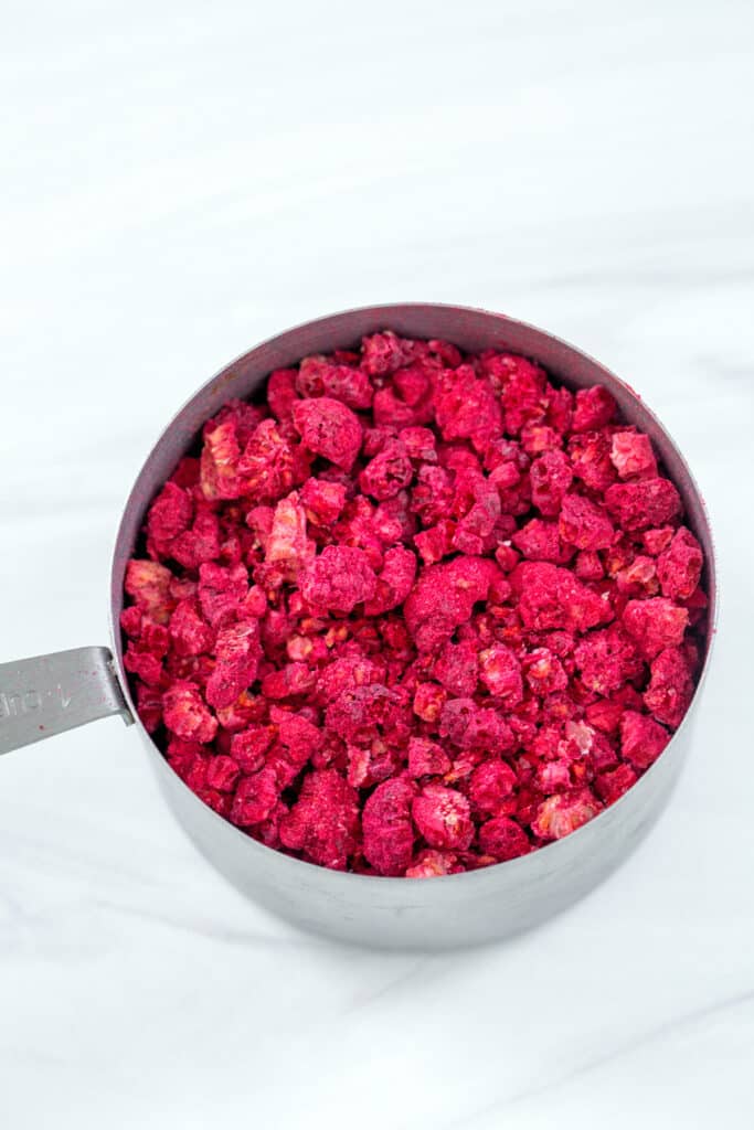 Crushed freeze-dried raspberries in measuring cup.