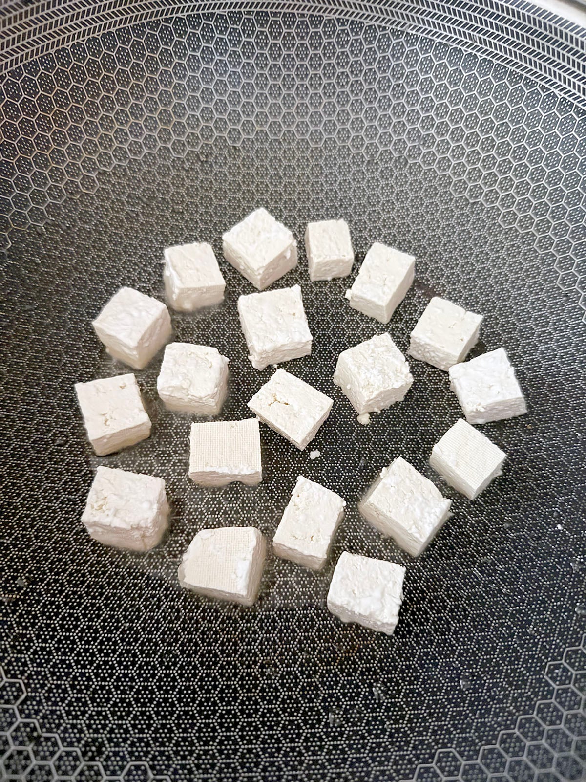 Cubed tofu in wok.