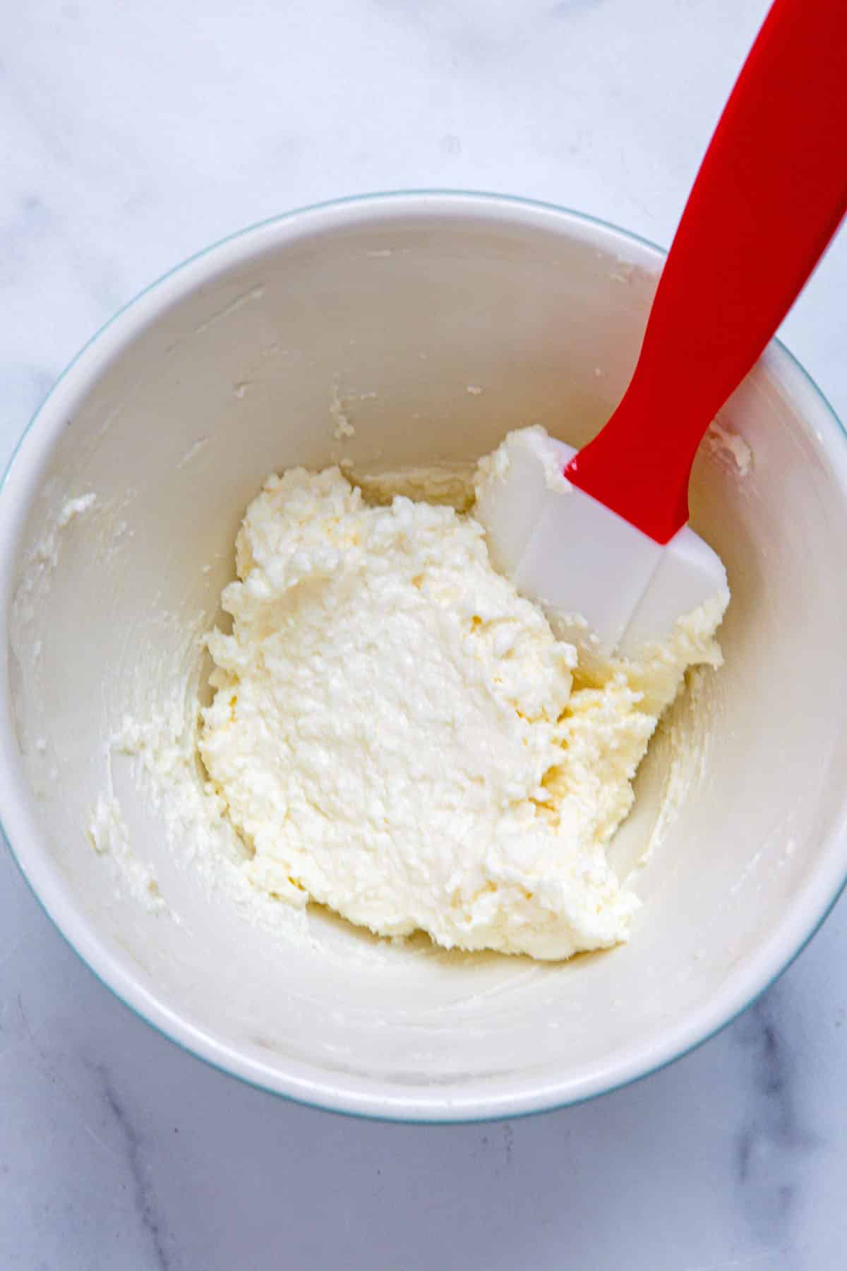 Sweet cream cheese filling in bowl with spatula.