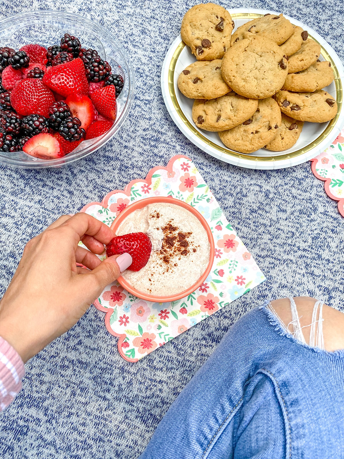 Hand dipping a fresh strawberry into cinnamon dip.