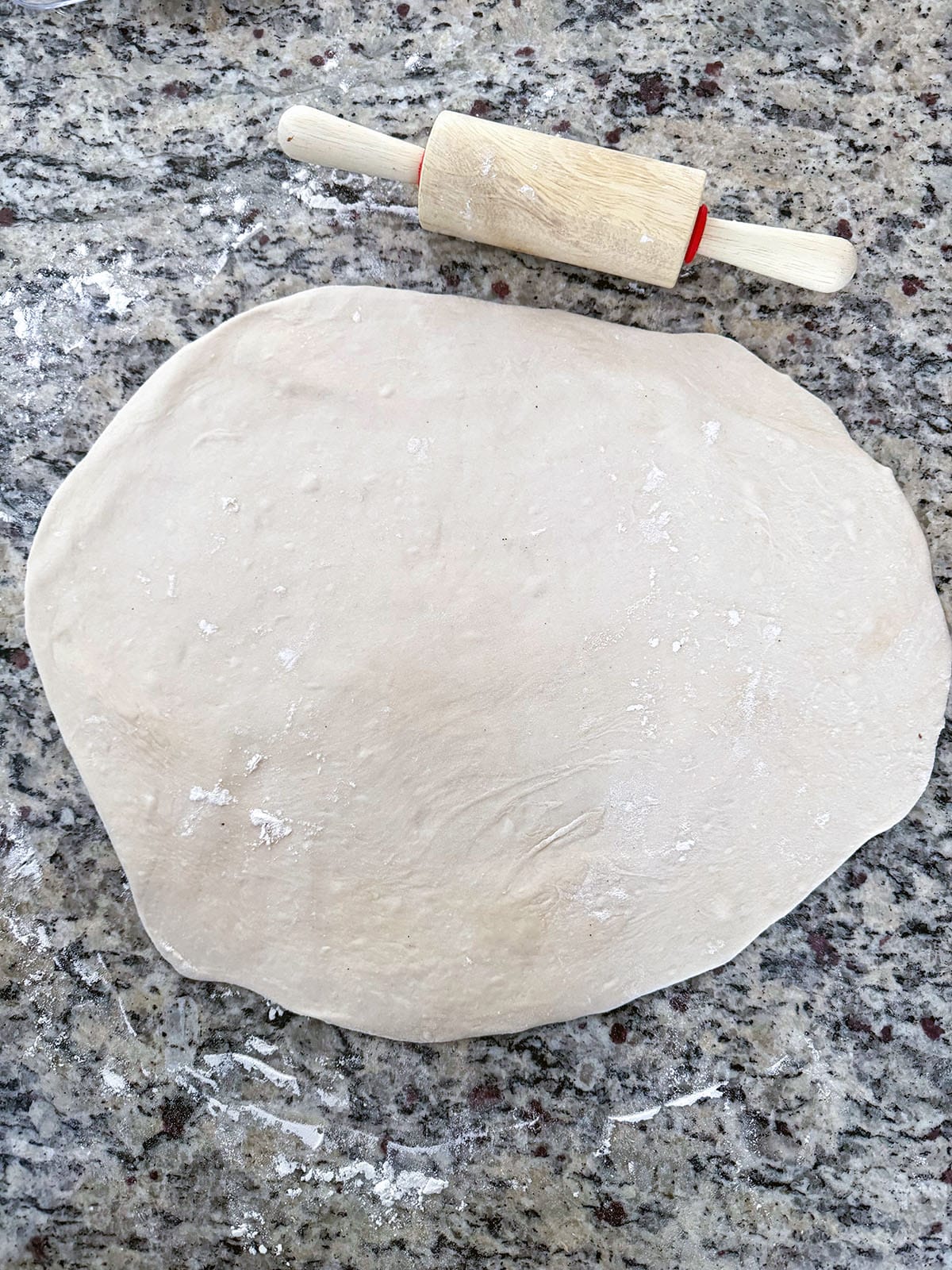 Pizza dough rolled out with rolling pin.