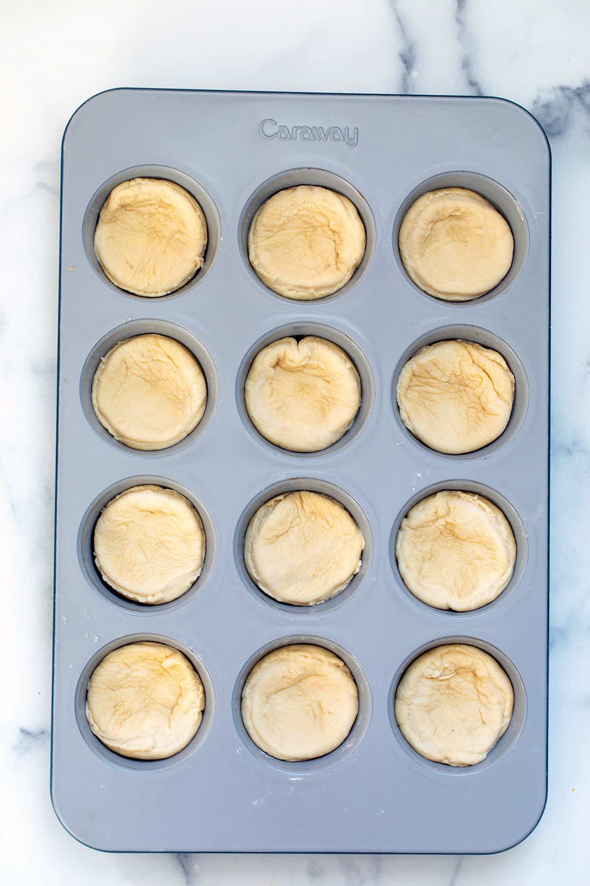 Cupcake tin with pizza dough pressed into it.