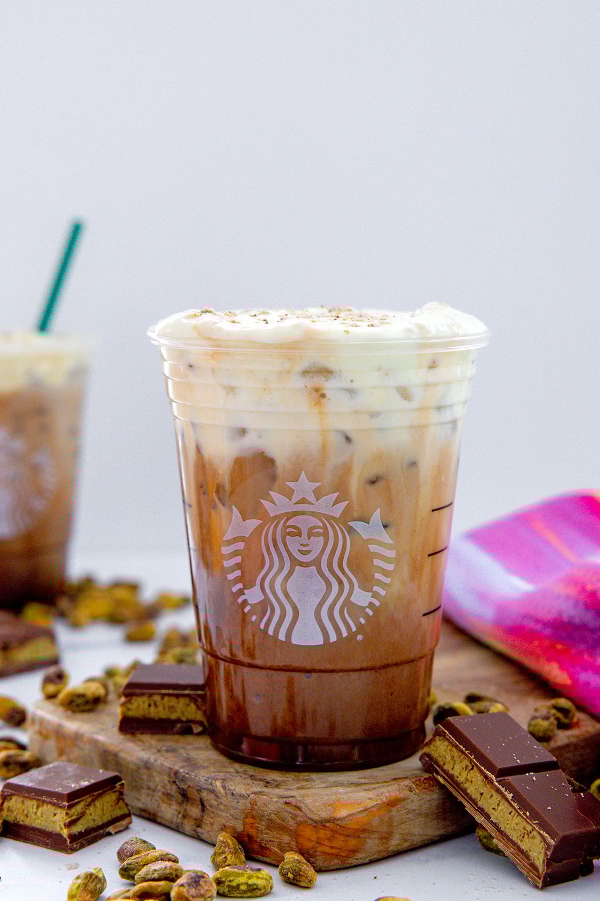 Head-on view of a Dubai Chocolate Mocha with chocolate bars and pistachios all around.