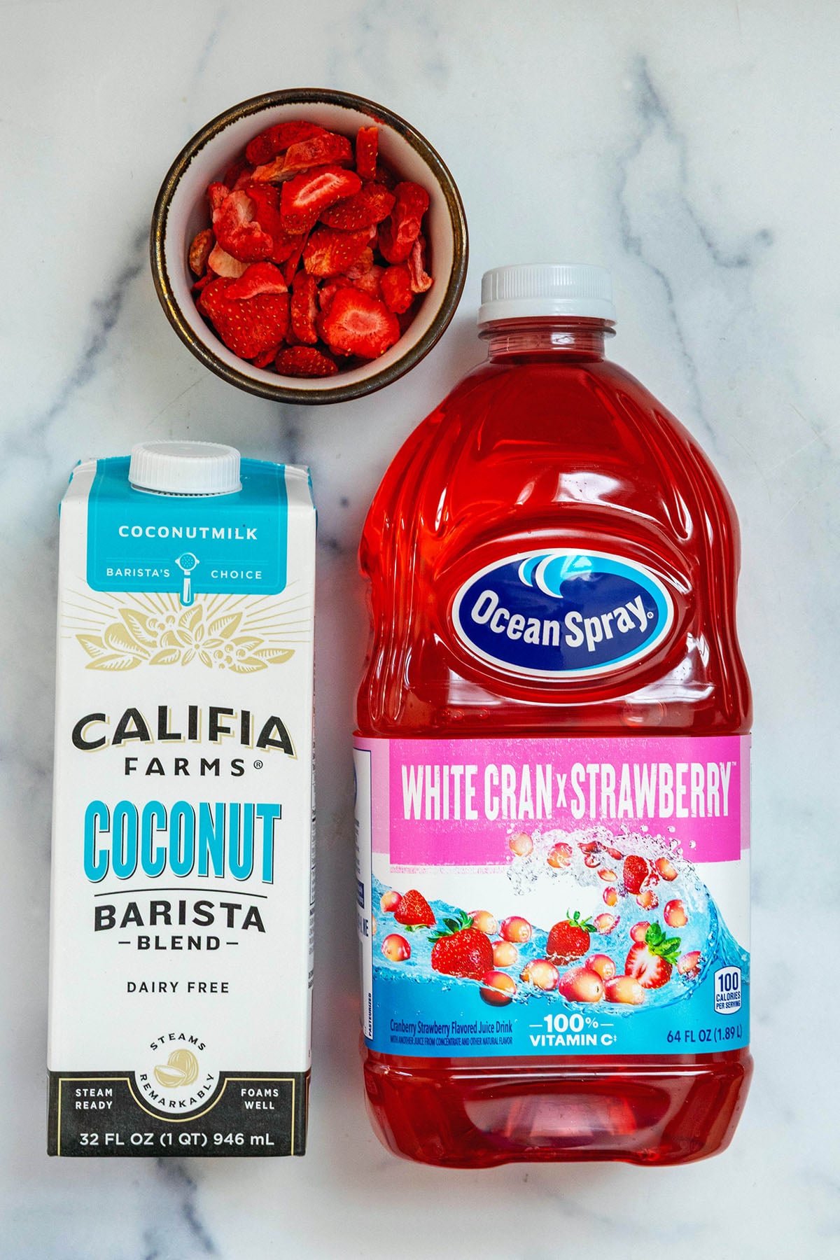Overhead view of Ocean Spray White Cran Strawberry juice, carton of coconut milk, and freeze-dried strawberries.
