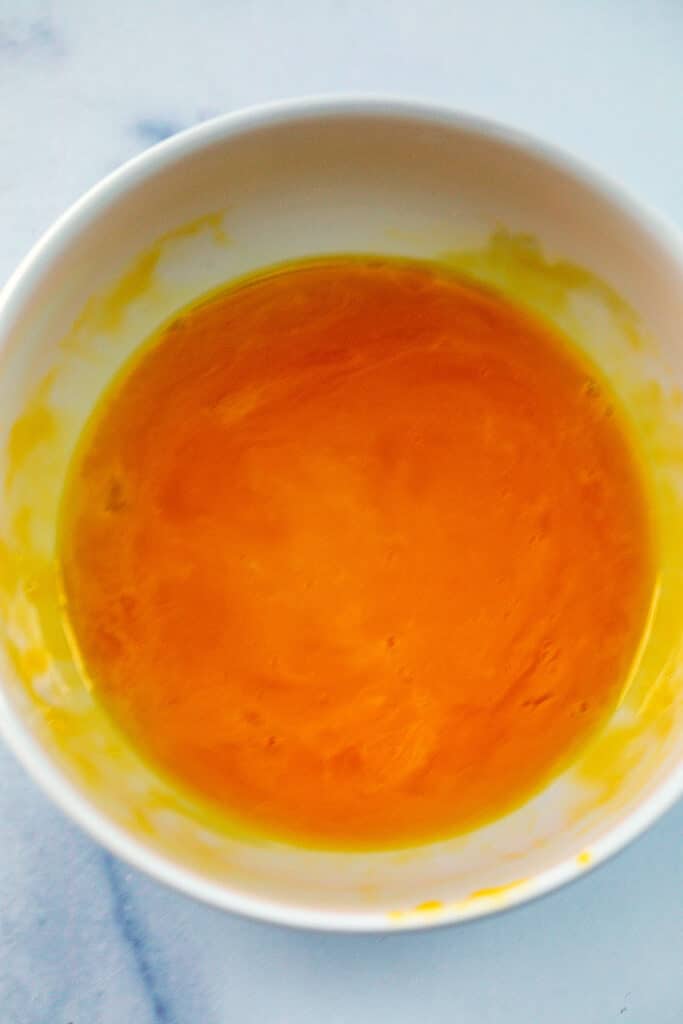 Egg yolks whisked together in bowl.