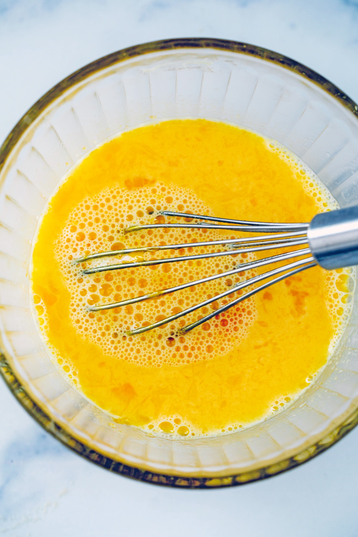Egg yolks whisked in bowl with warm milk to temper them.