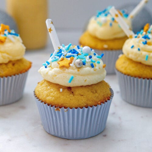 Closeup head-on view of an eggnog cupcake with buttercream and sprinkles.