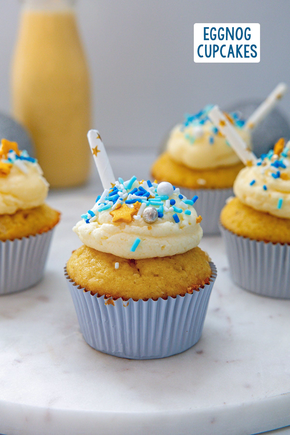 Head-on view of an eggnog cupcake with more cupcakes in background and recipe title at top.