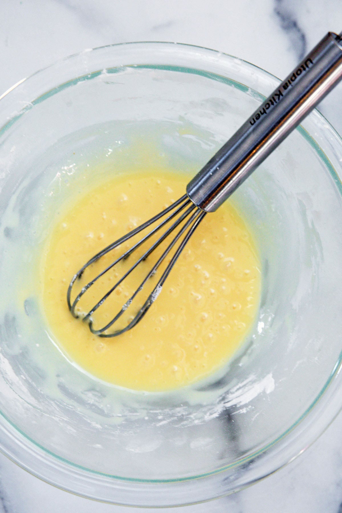 Eggnog icing in bowl with whisk.