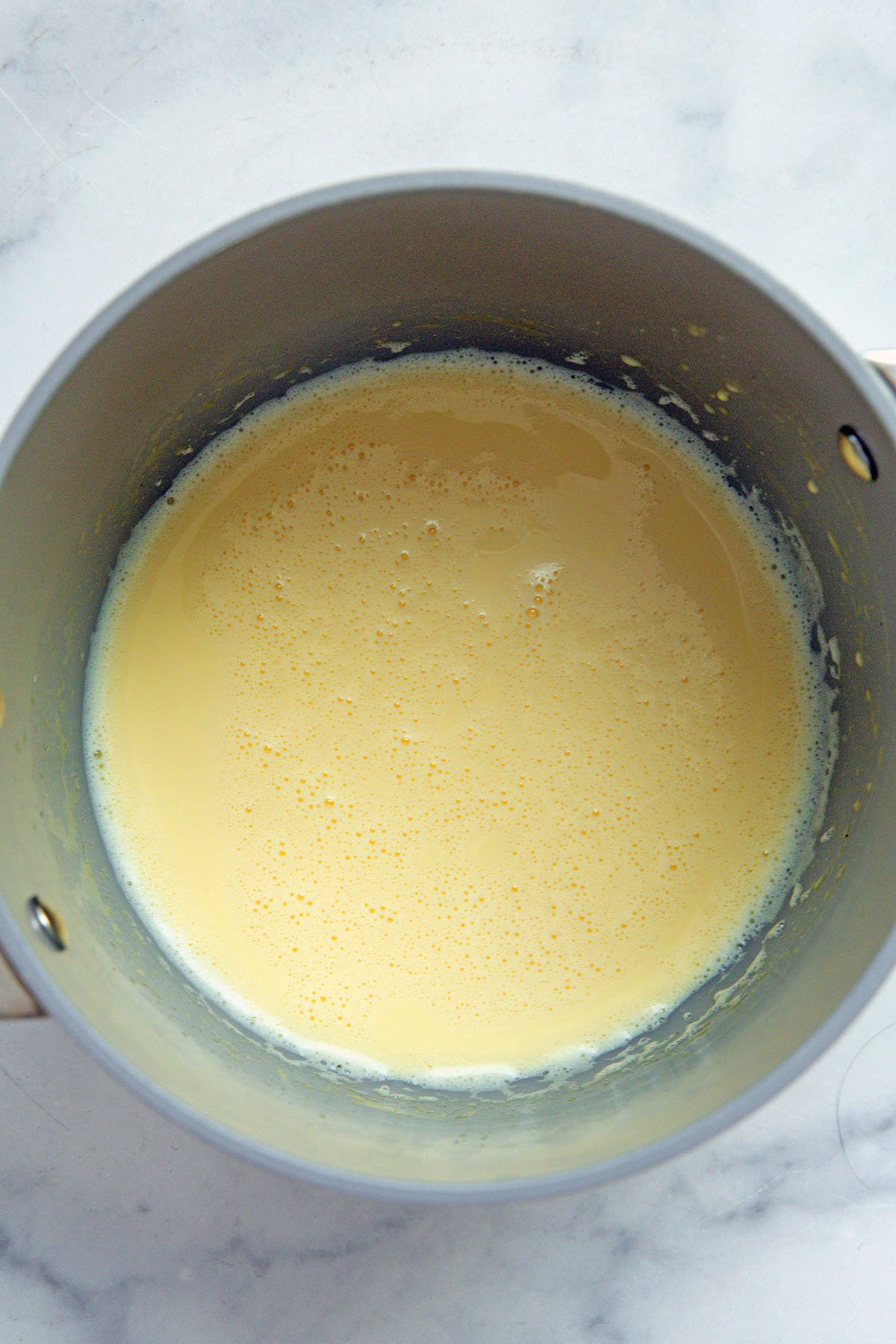 Steamed eggnog and milk in saucepan.