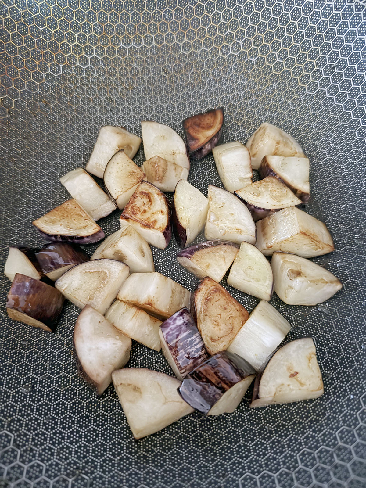 Eggplant chunks caramelizing in wok.