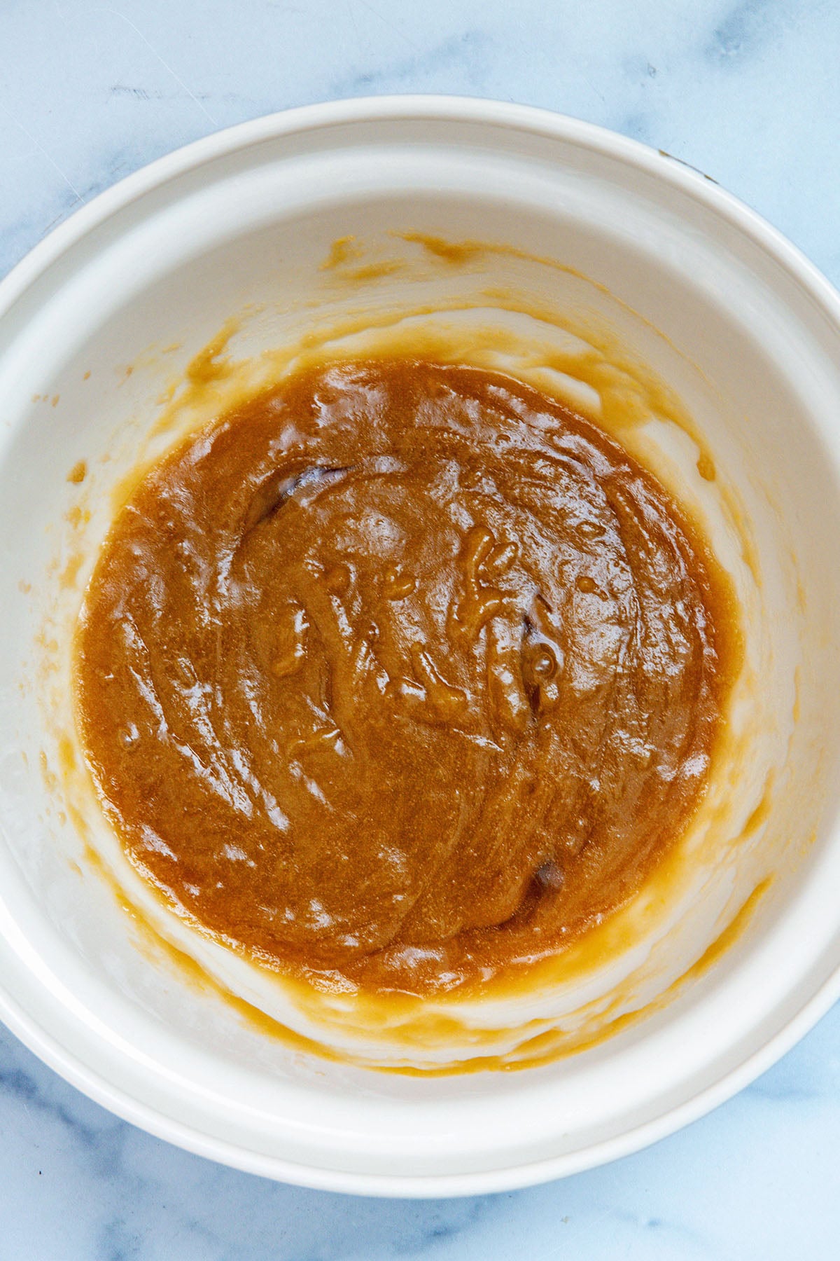 Melted butter, sugars, and eggs in a mixing bowl.