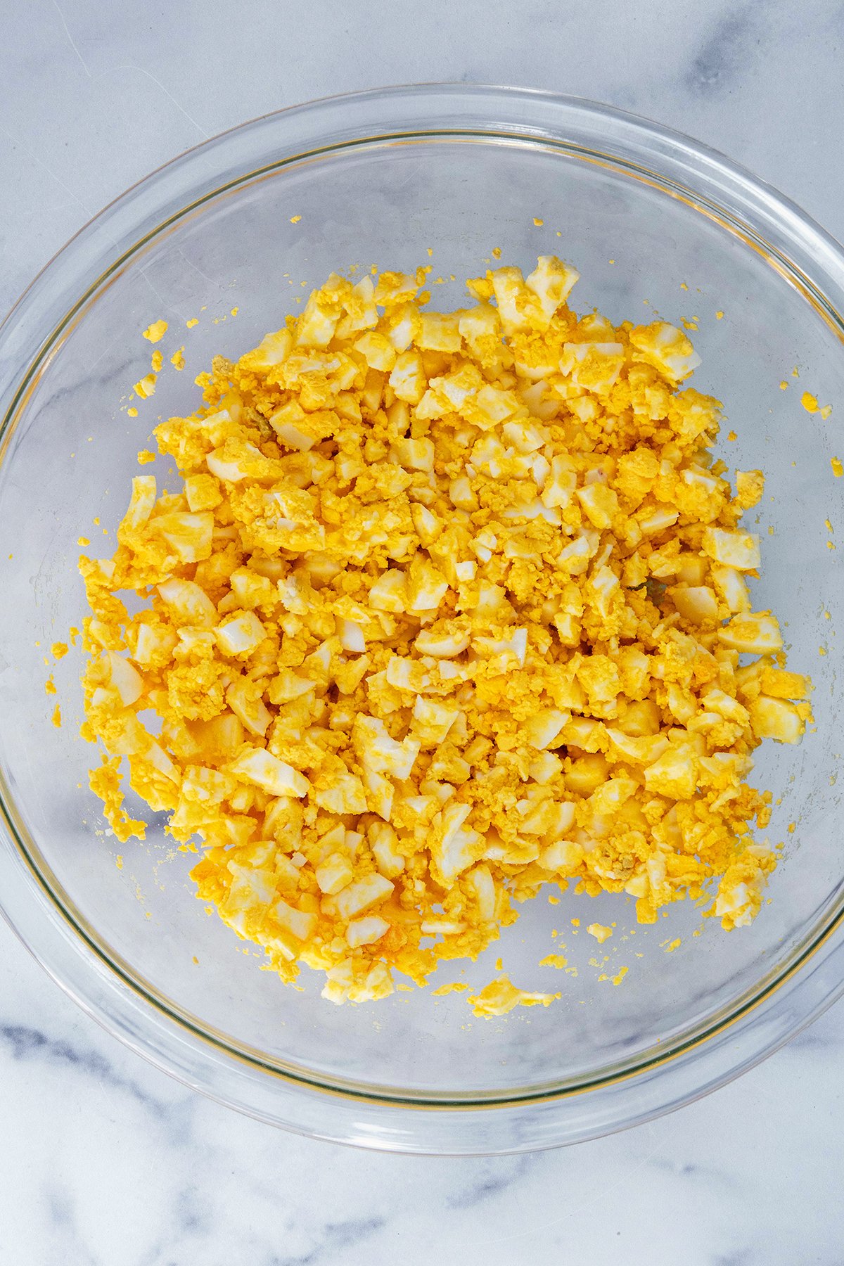 Hardboiled eggs mashed up in bowl.