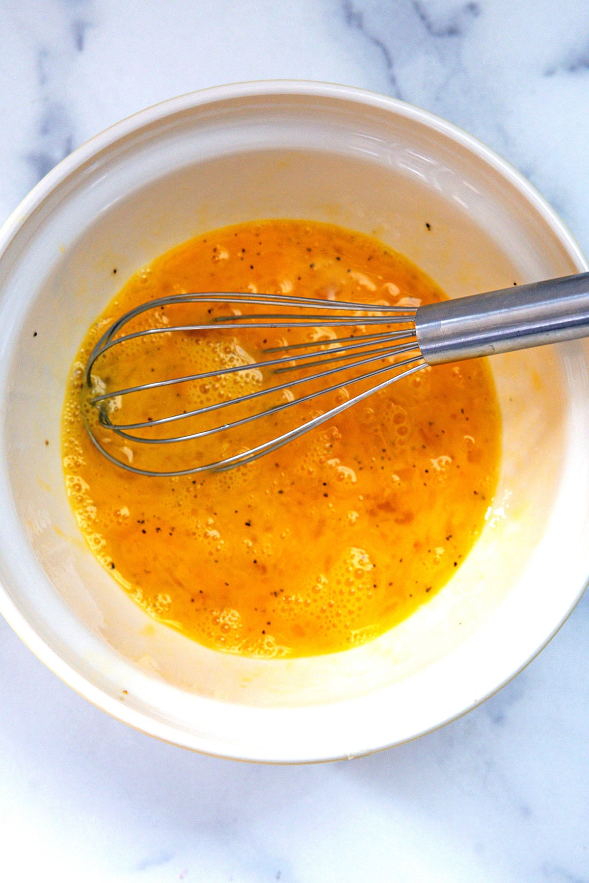 Egg scrambled with whisk in mixing bowl.