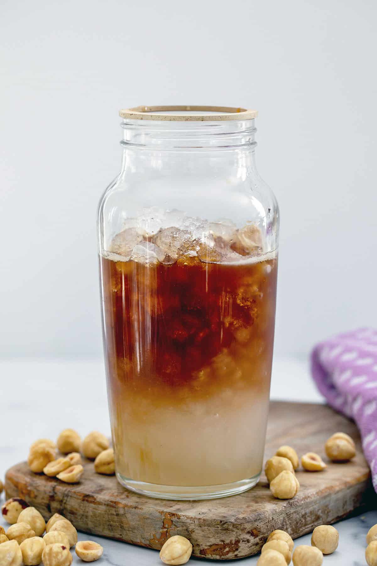 Ice, hazelnut syrup, and espresso in a glass shaker.