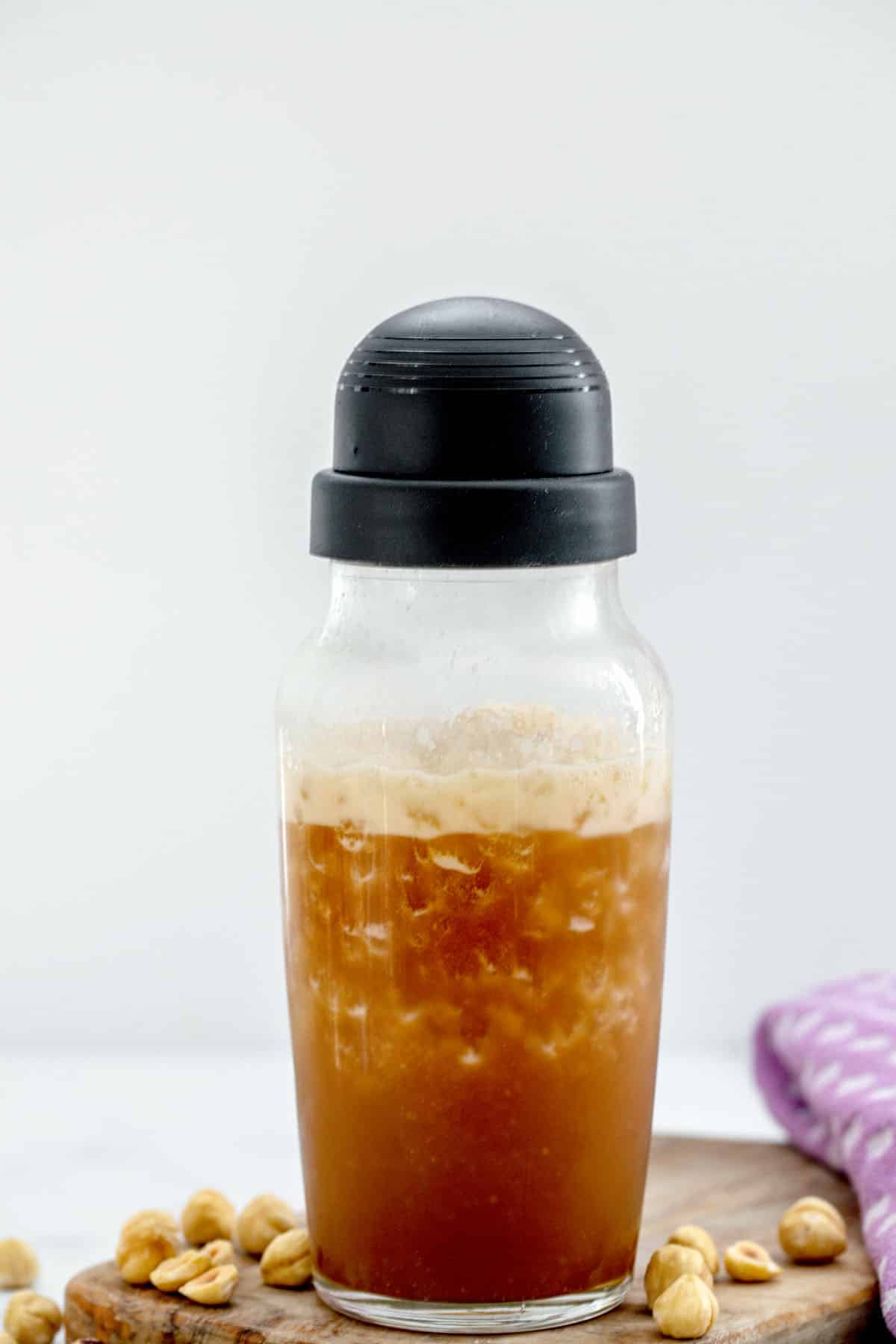 Clear shaker with hazelnut syrup and espresso shaken together with ice.