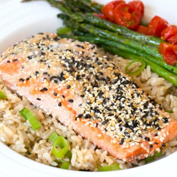 Closeup view of everything bagel salmon over coconut rice with asparagus and tomatoes.