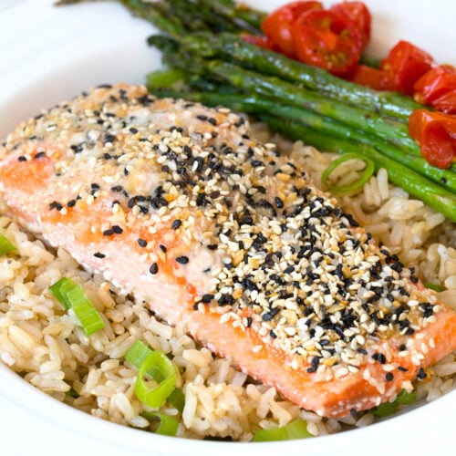 Closeup view of everything bagel salmon over coconut rice with asparagus and tomatoes.