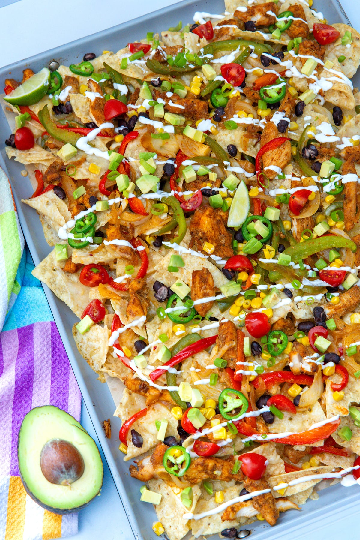 Overhead view of chicken fajita nachos with avocado half on the side.